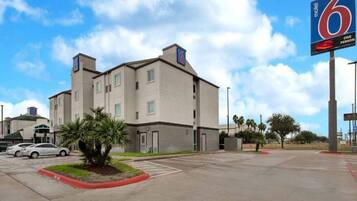 Un motel con un letrero grande, un estacionamiento y un edificio con varias ventanas.