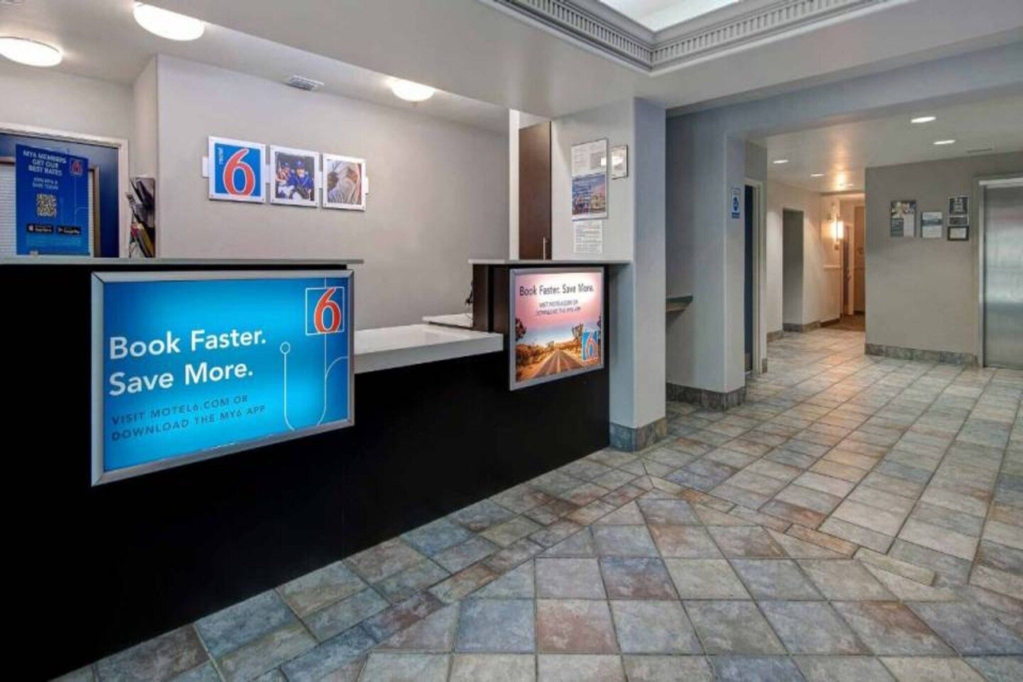A reception area with a digital display board, a tiled floor, and a hallway leading to other rooms.