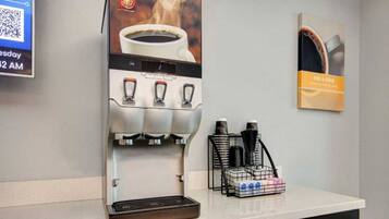 A coffee machine with a cup of coffee and a poster on the wall.