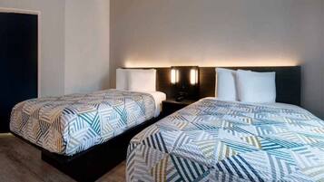 Habitación de hotel con dos camas, cada una con una colcha estampada, lámparas de noche y cabeceros oscuros.