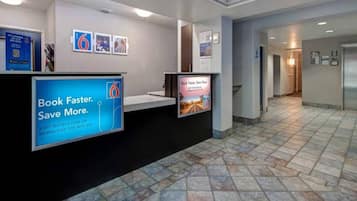 A reception area with a digital display board, a tiled floor, and a hallway leading to other rooms.