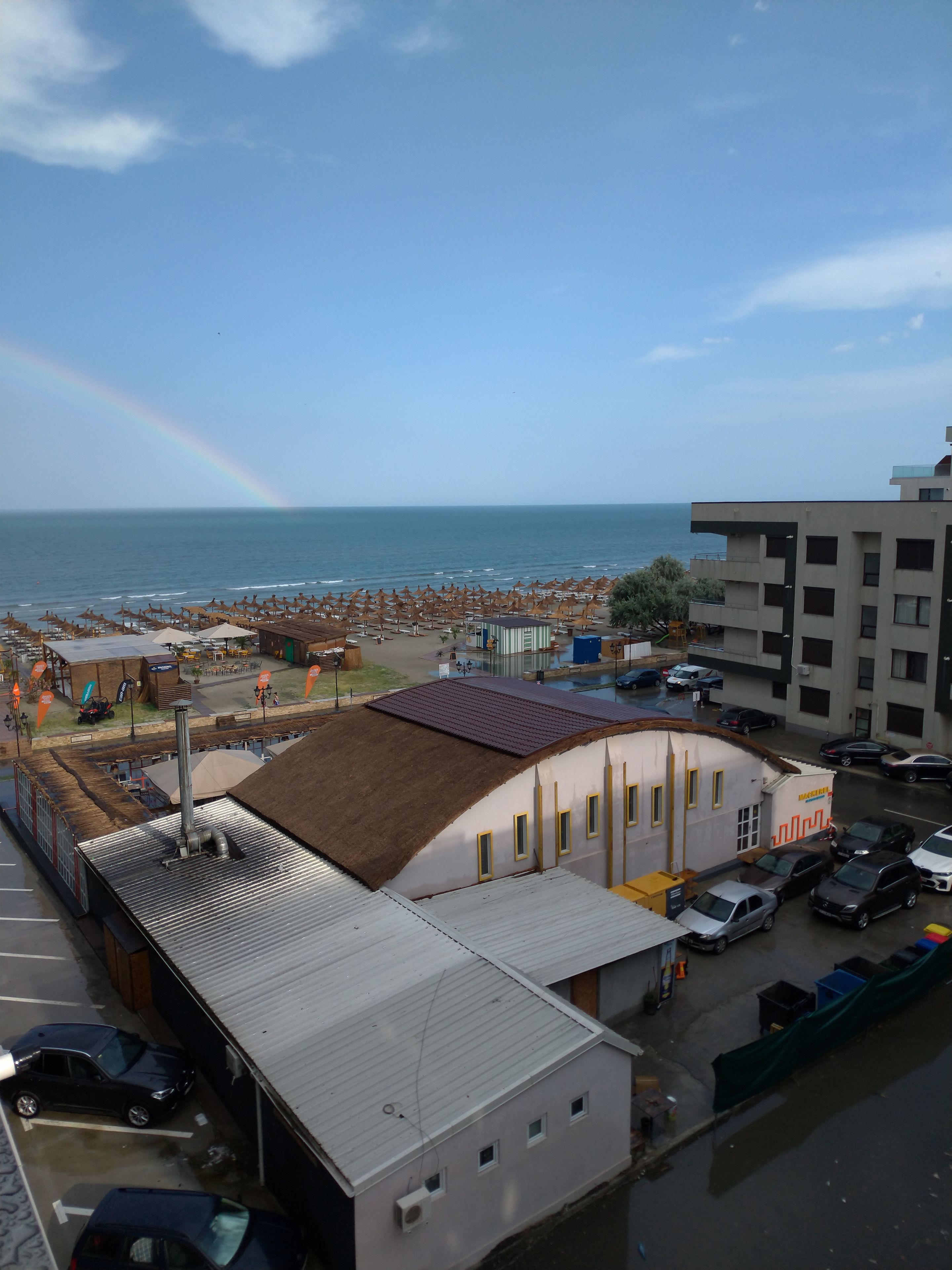 Une vue sur la côte, avec une plage, des parasols et un bâtiment doté d’un toit plat.