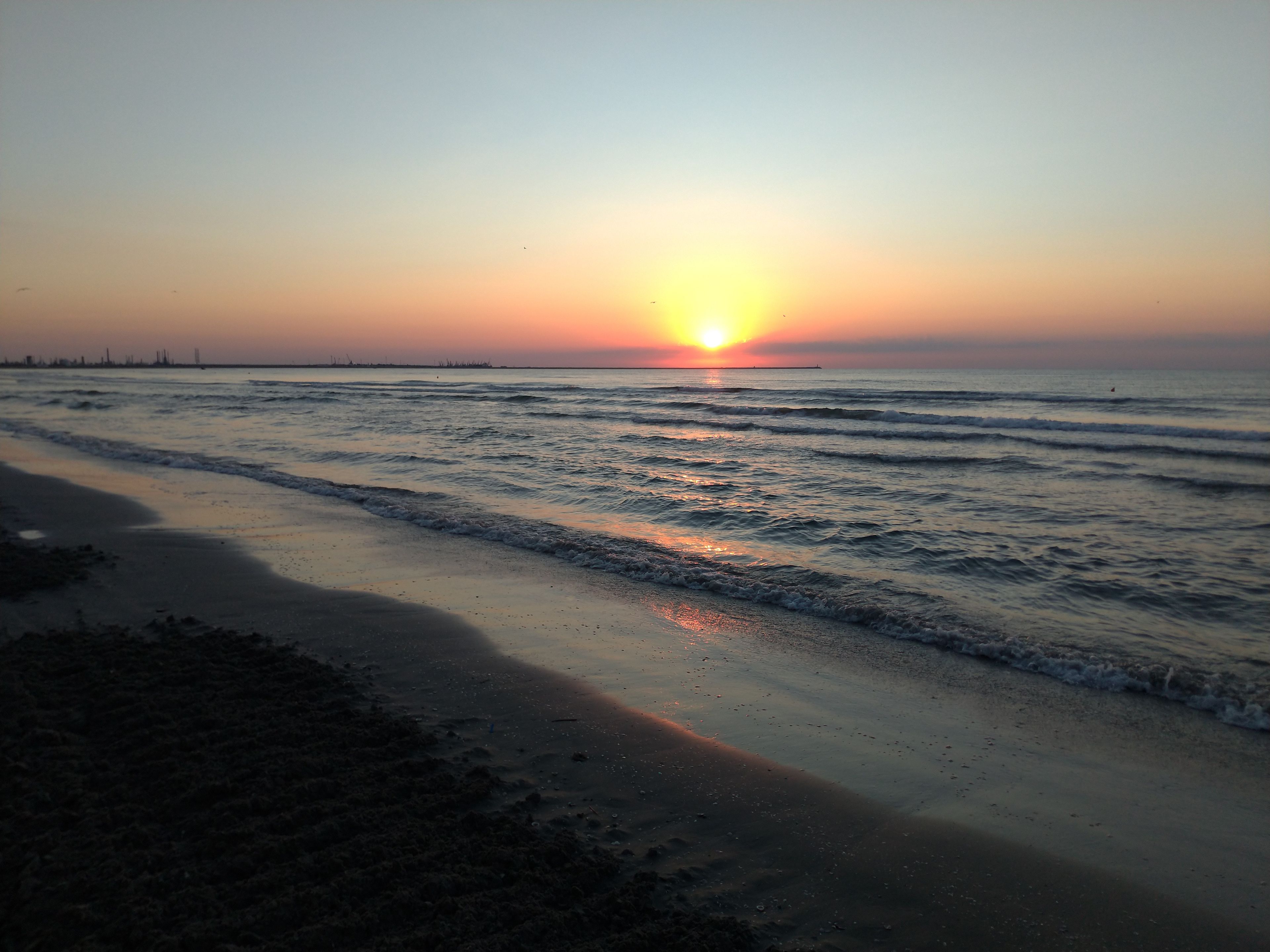 A beach at sunset with waves gently lapping the shore.