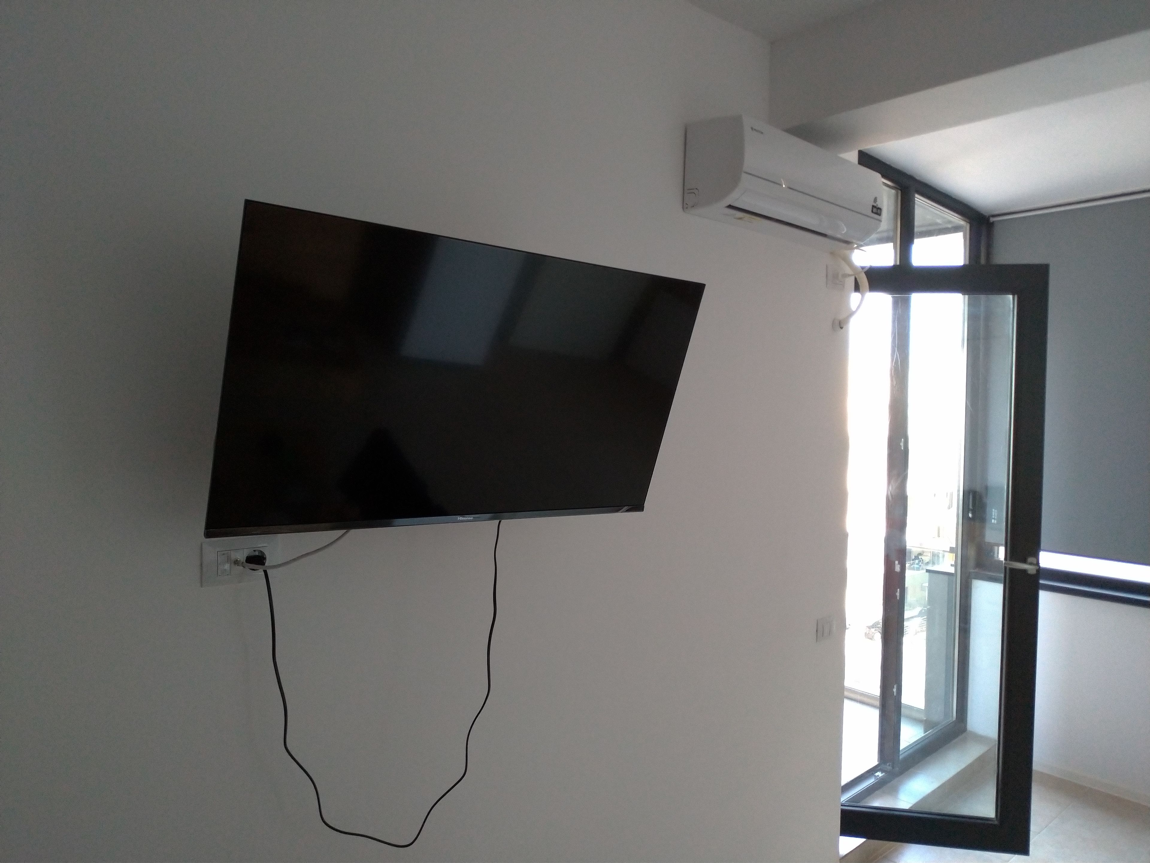 A flat-screen TV mounted on a wall with a cable connected to it.