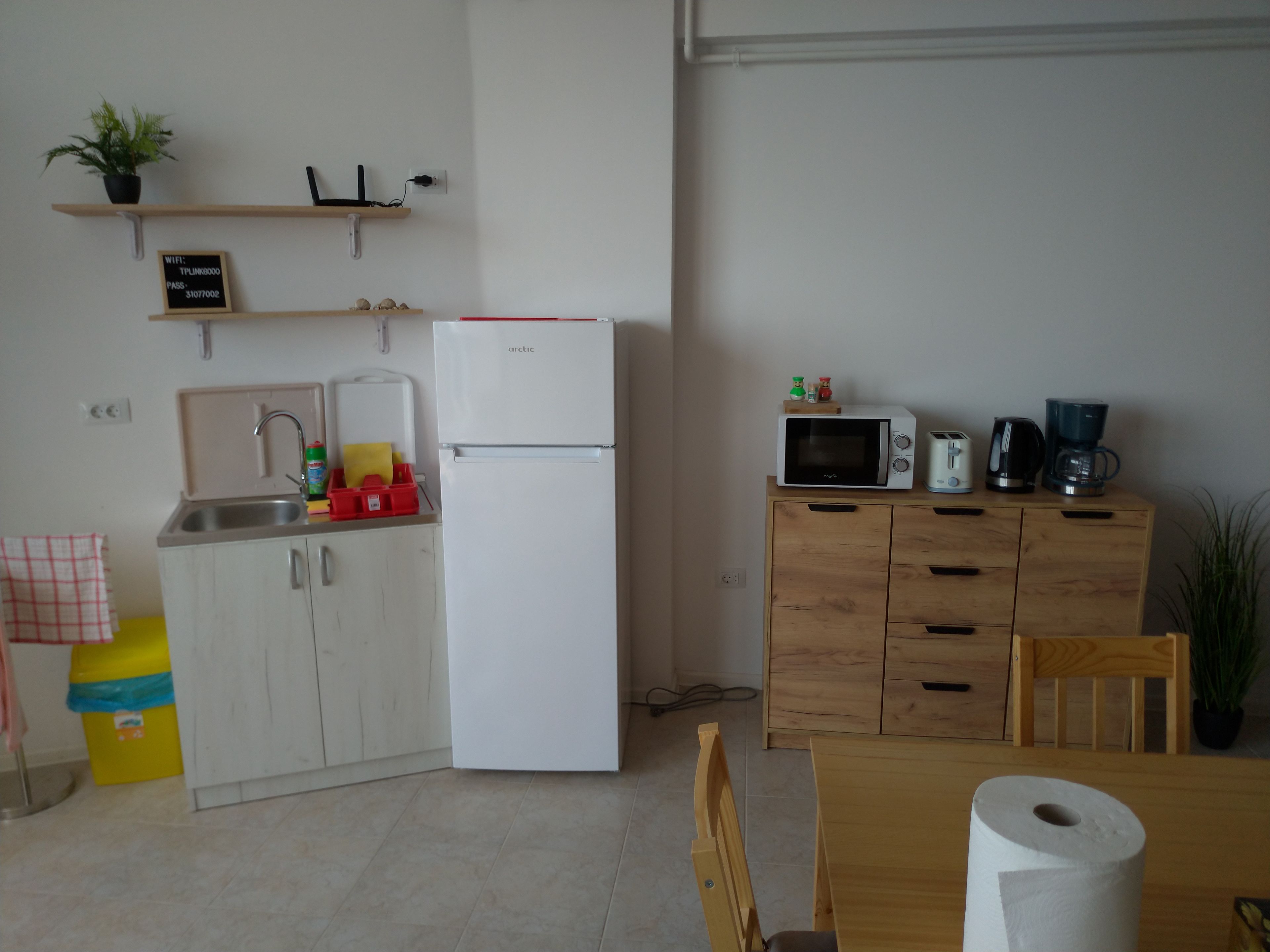 A compact kitchen with a white refrigerator, a microwave, and a coffee maker on a wooden cabinet.