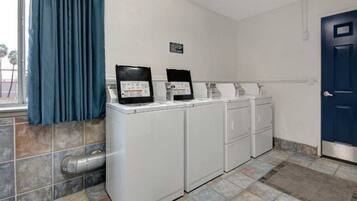 A laundry room with a washing machine, dryer, and stacked laundry baskets.