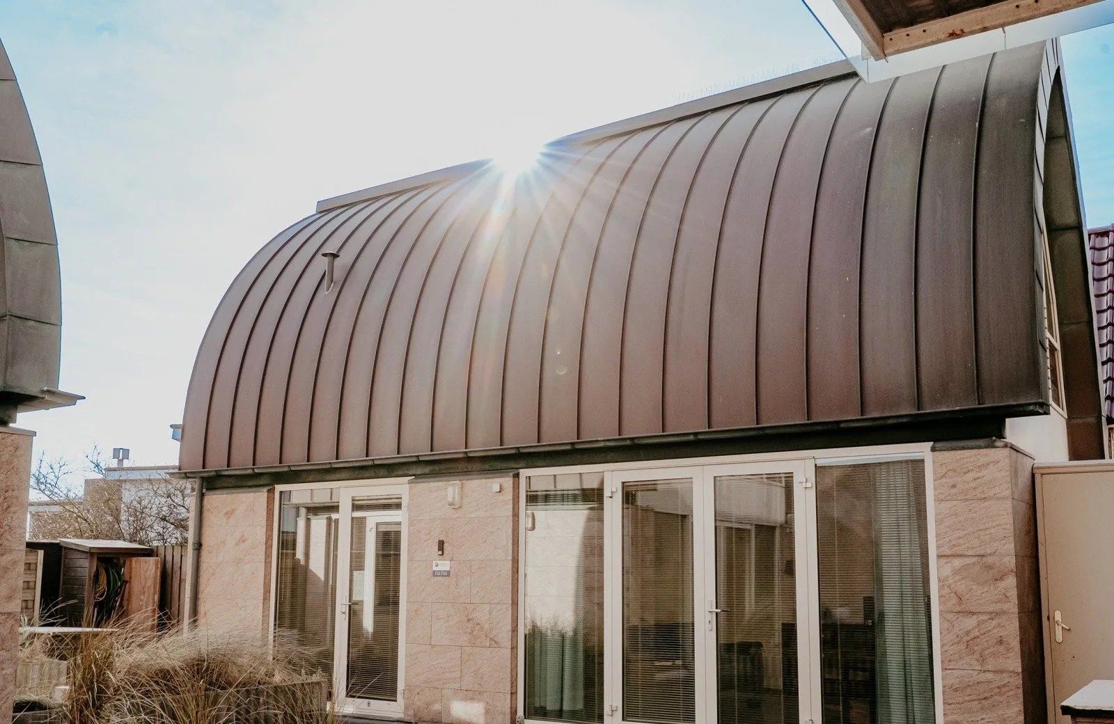 Ein Gebäude mit einem gewölbten Metalldach und großen Glasfenstern.