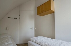 A bedroom with a single bed, a wooden wardrobe, and a door. - Sea-view apartment Sea Bass in Egmond aan Zee for 4 guests, with 2 bedrooms and two sunny terraces. (Egmond aan Zee)