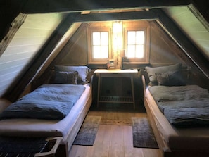 A small attic bedroom with two single beds, a wooden desk, and a window. - Holiday Home The old Barn (Schneverdingen)