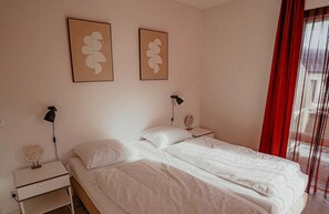A bedroom with a bed, two bedside tables, a lamp, and a wall-mounted fan. - Luxury coastal apartment Crab in Egmond aan Zee for 6 guests, with 3 bedrooms, a balcony and panoramic sea views. (Egmond aan Zee)