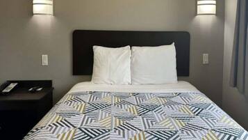 A hotel room with a bed, two bedside lamps, a nightstand, and a telephone.
