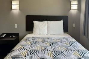 Una habitació d'hotel amb un llit, dues làmpades de nit, una taula de nit i un telèfon.