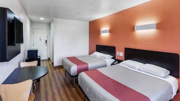 Ett hotellrum med två sängar, ett skrivbord och en TV.