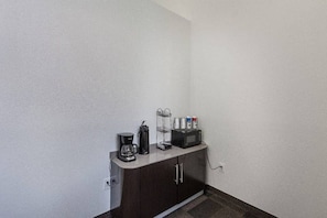 Une petite cuisine équipée d’une machine à café, d’un four à micro-ondes et d’un petit réfrigérateur.