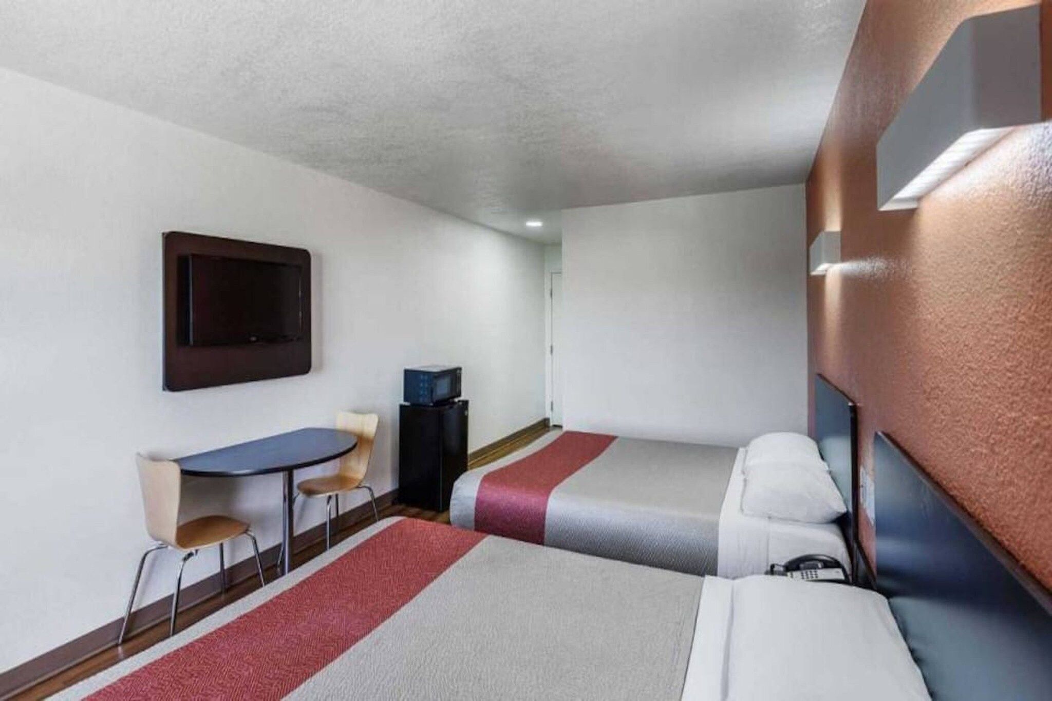 A hotel room with a bed, a desk, a chair, a television, and a small table.