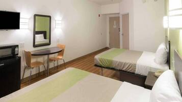 Habitación de hotel con dos camas, un escritorio con silla, televisión y espejo.