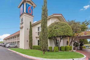 A motel with a prominent tower displaying the number 6, a parking lot, and a well-maintained lawn. - 2 Full Beds | Smoking (Dallas)