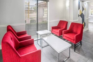 A modern interior with red upholstered chairs, a white table, and a large window with blinds. - 2 Full Beds | Smoking (Dallas)