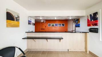 A reception area with a counter, a chair, and a wall with posters.