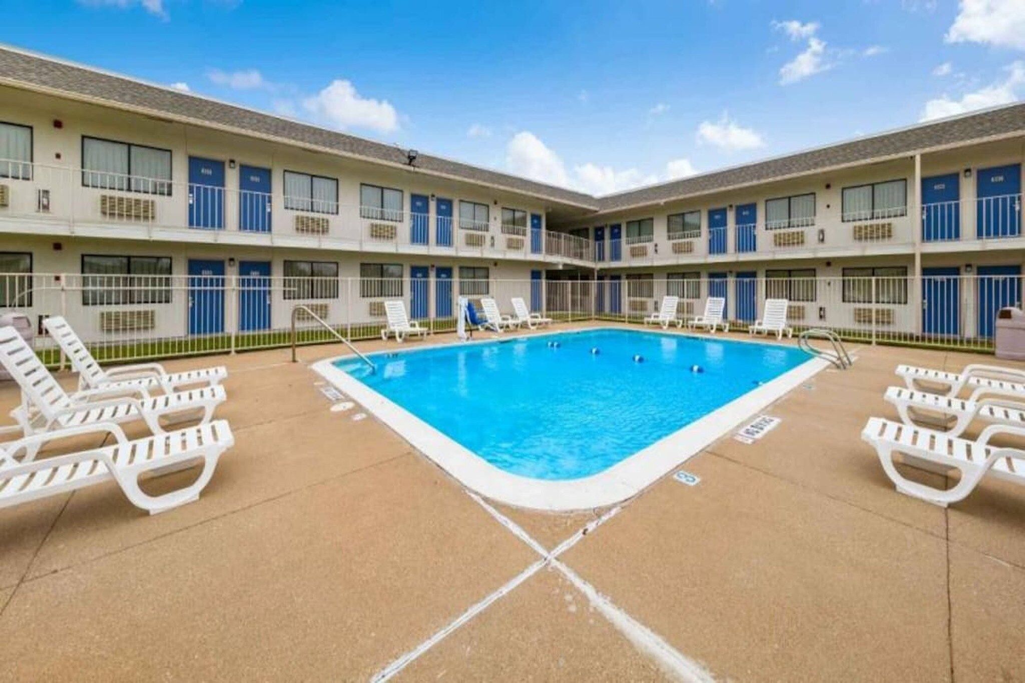 A hotel with a central swimming pool surrounded by lounge chairs.