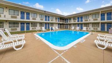 A hotel with a central swimming pool surrounded by lounge chairs.