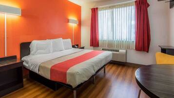 A hotel room with a bed, bedside tables, a desk, and a chair.