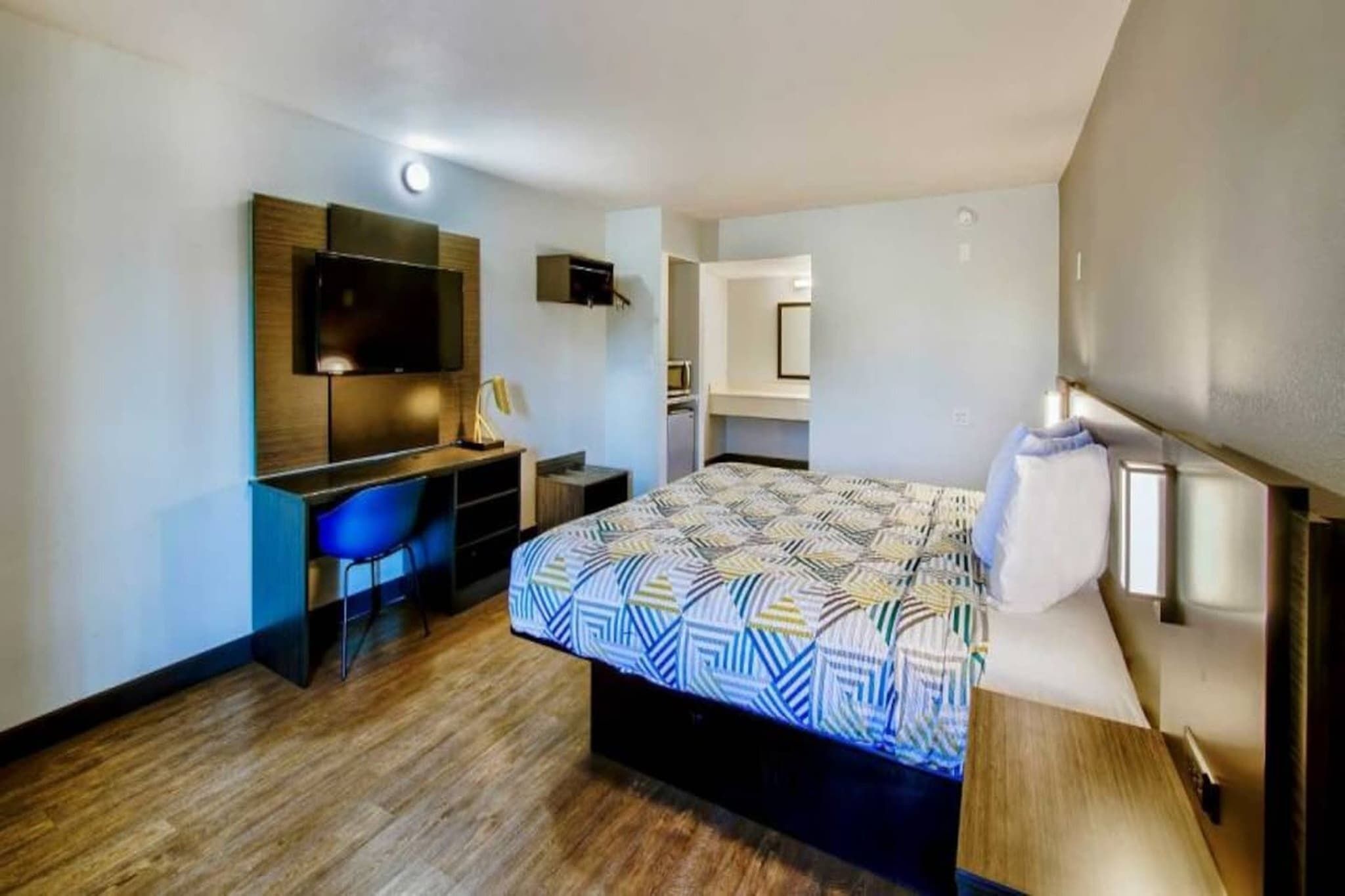 Una camera d'albergo con un letto, una scrivania, una sedia, una televisione e un forno a microonde.