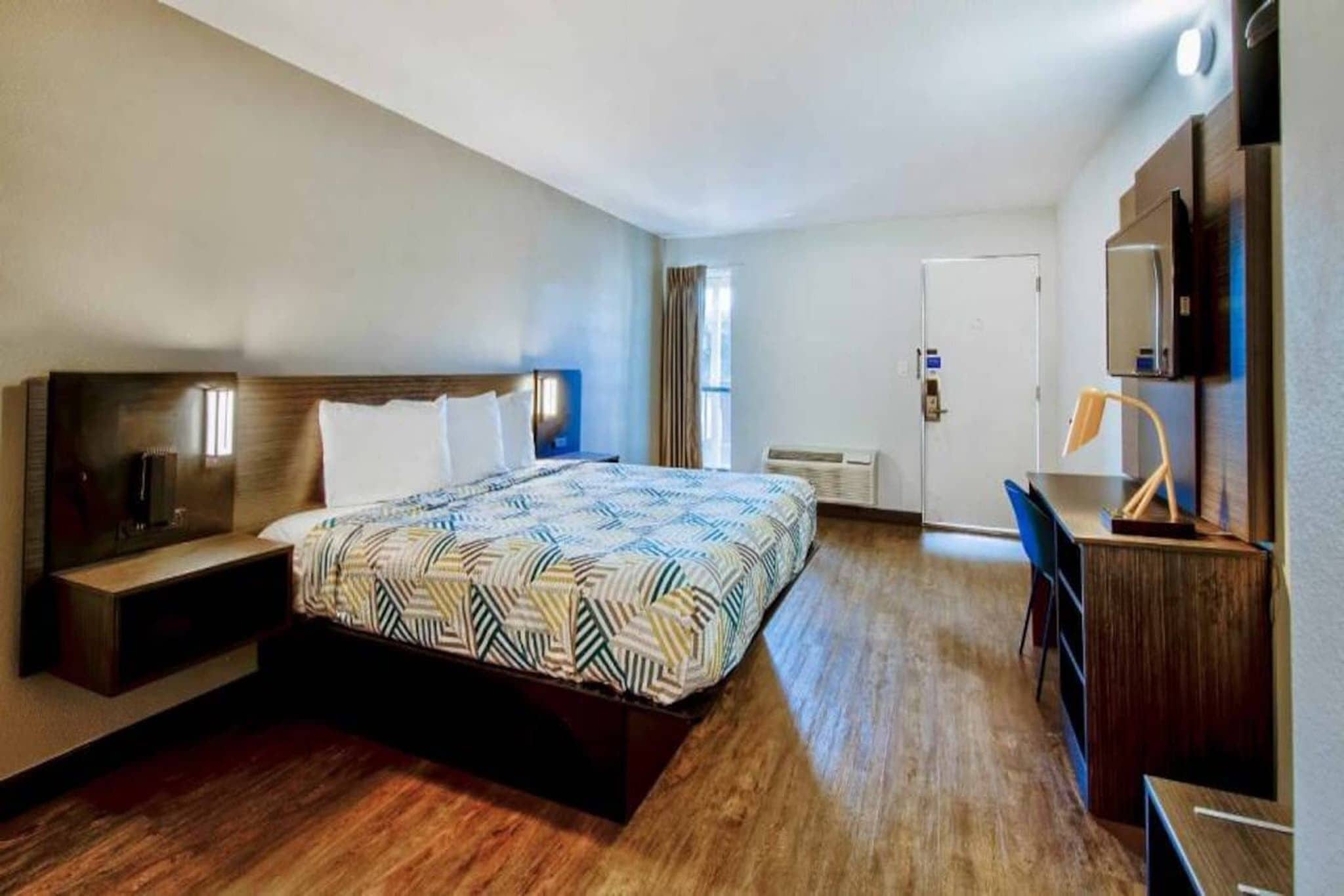 Une chambre d’hôtel comprenant un lit, un bureau, une chaise, une armoire et un téléviseur.