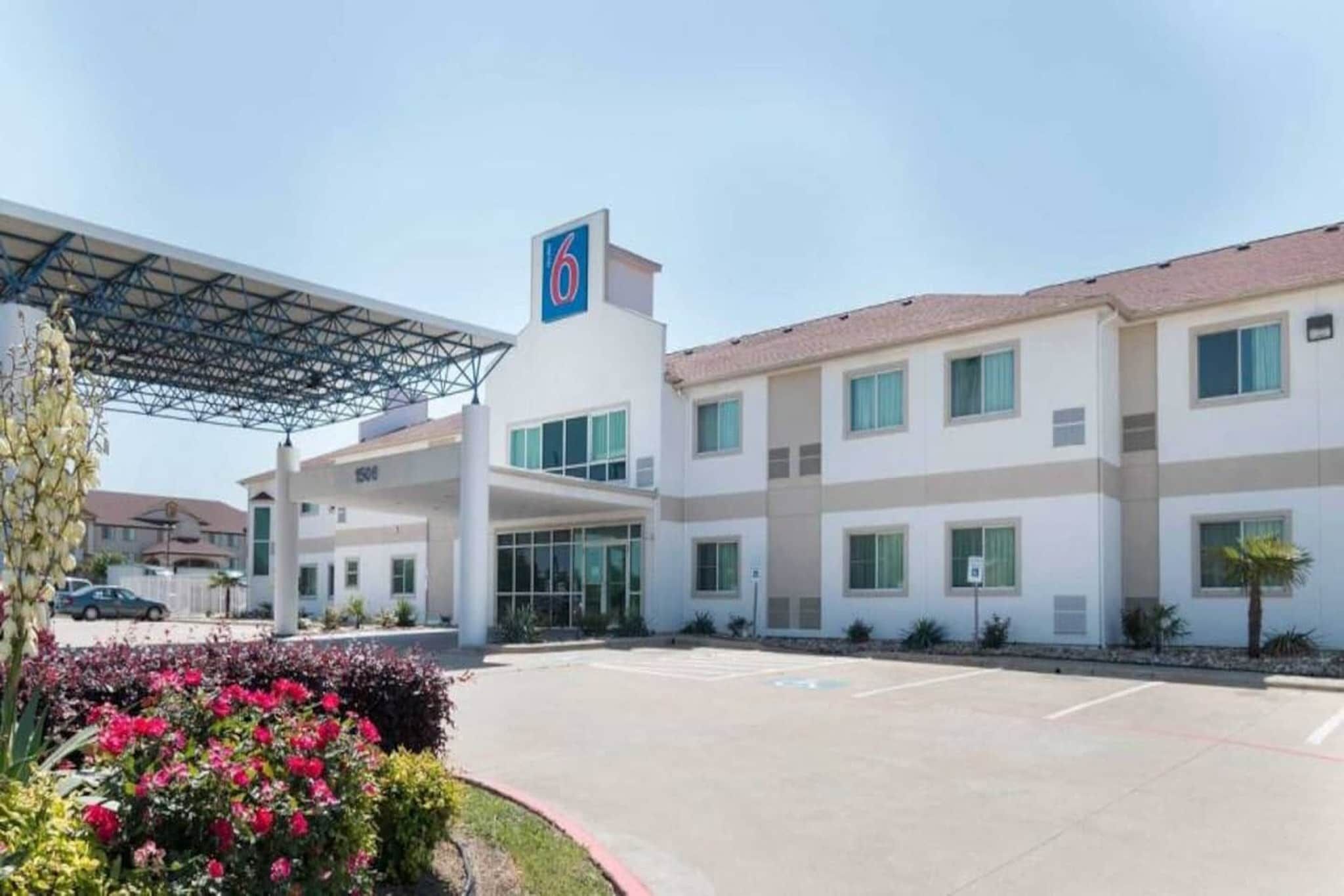 A hotel with a covered parking area, a large entrance, and a building with multiple windows.