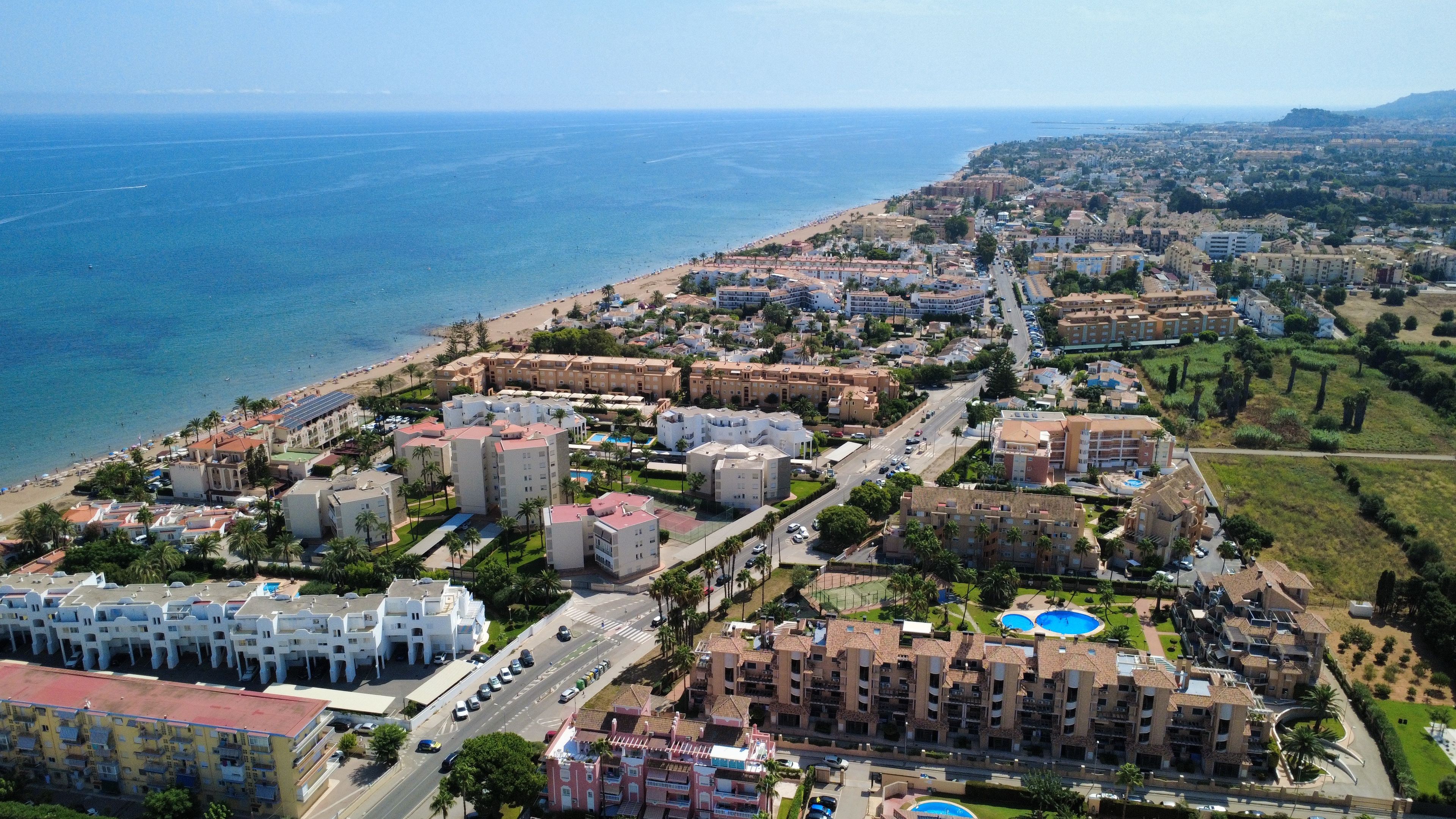 Un paisaje urbano costero con una playa, edificios residenciales y una carretera.