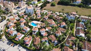 A residential area with multiple houses, a swimming pool, and parked cars.