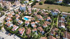 Una zona residencial con varias casas, una piscina y coches estacionados.