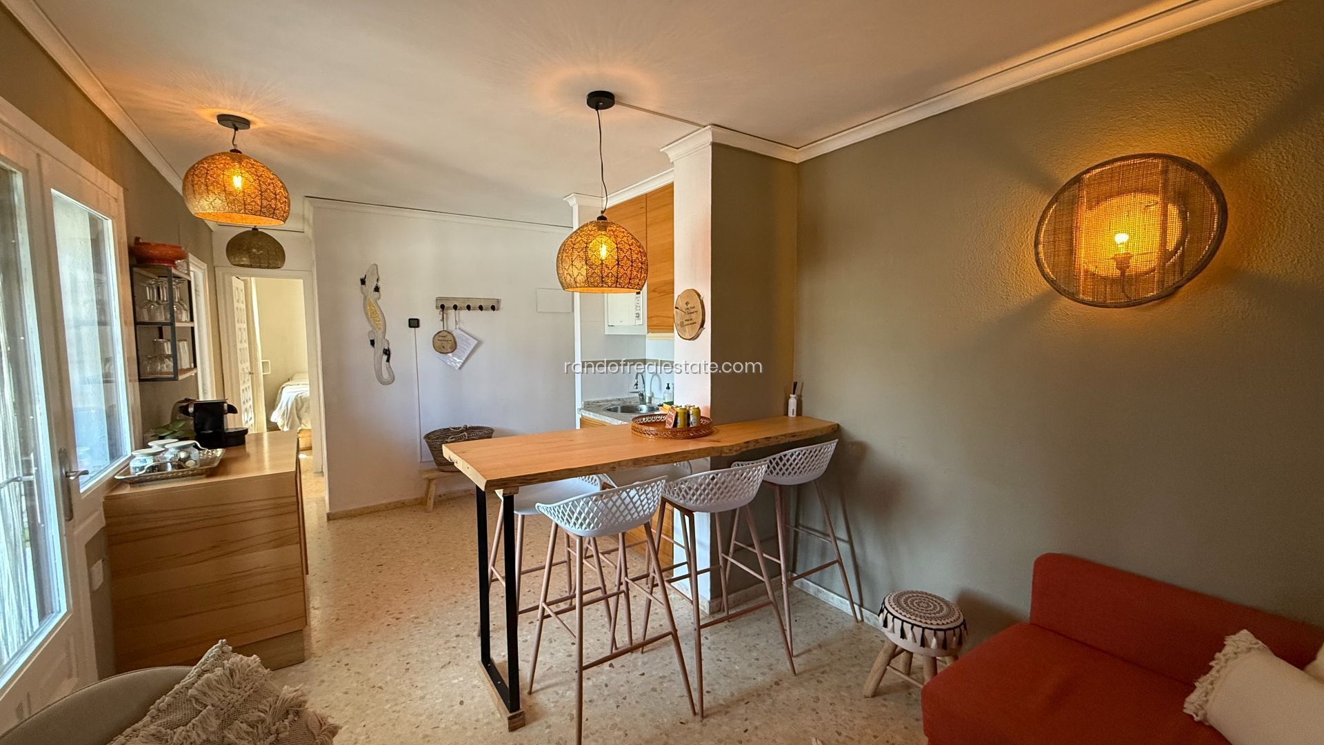 Una cucina accogliente con un tavolo di legno e sgabelli da bar, un divano rosso e un lampadario.
