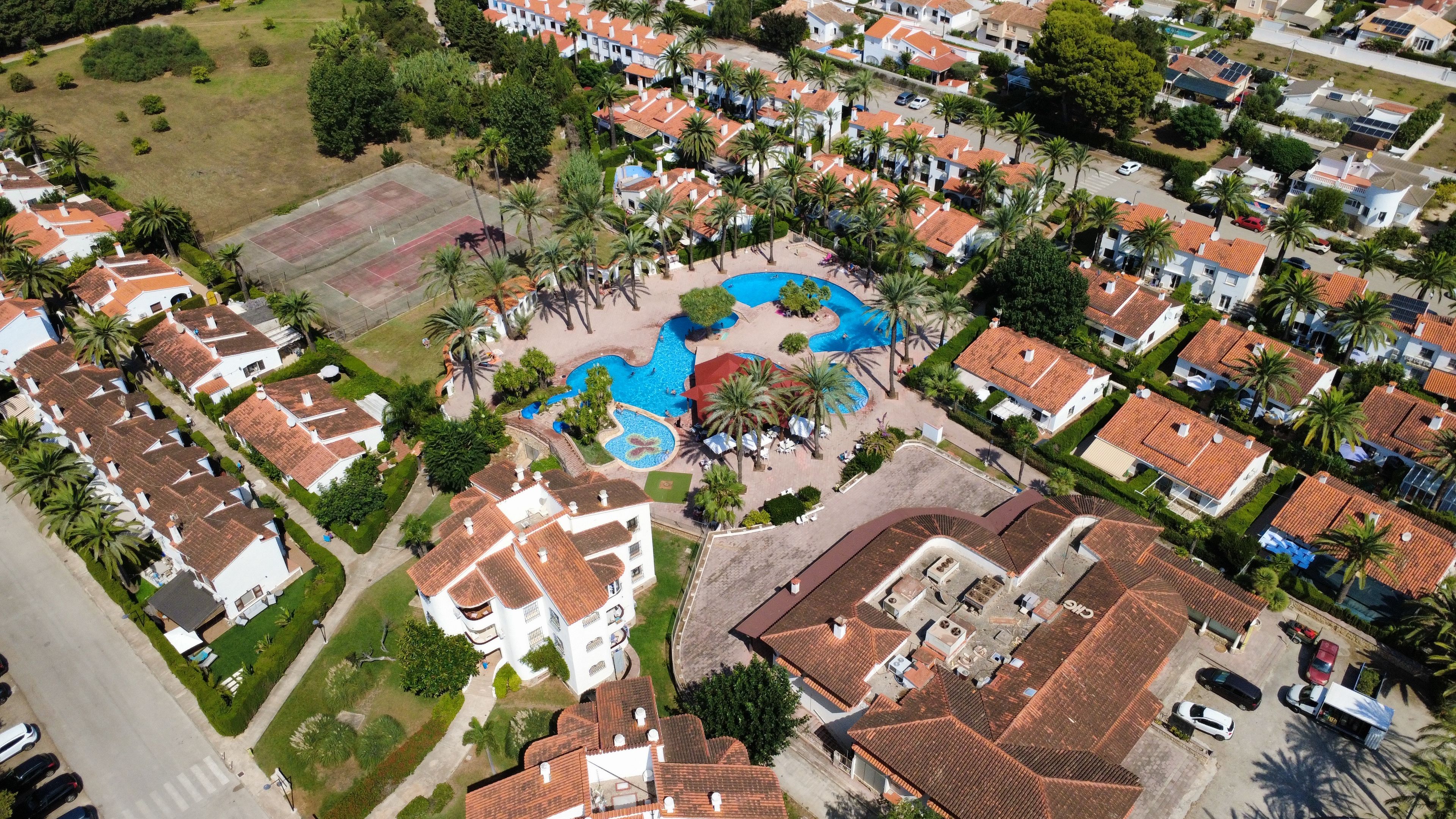 Vista aérea de uma área residencial com casas, piscina e campo esportivo.