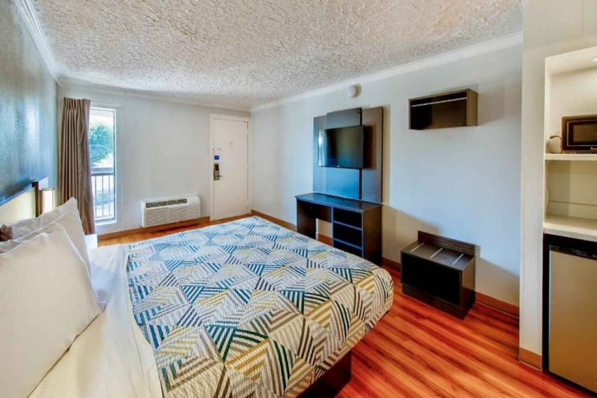 Una camera d'albergo con un letto, una televisione, una scrivania e un armadio.