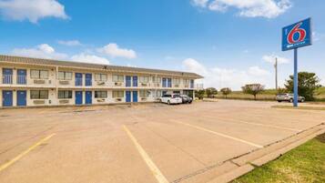 A motel with multiple rooms, a parking lot, and a clear sky.
