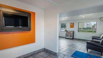 A reception area with a tiled floor, a blue mat, a clock, and a seating area with chairs.