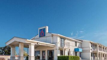 A motel with a prominent '6' sign, multiple balconies, and a parking lot.