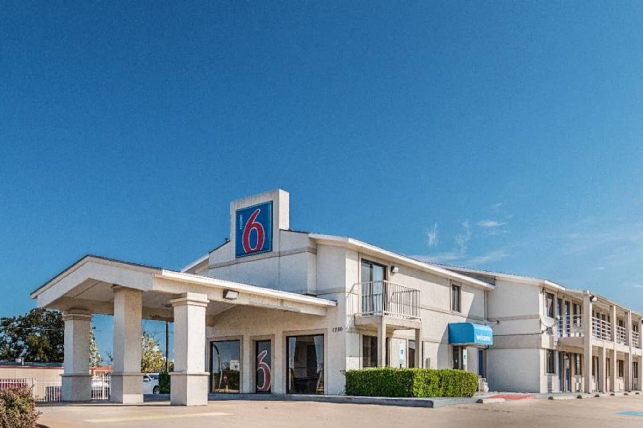 A motel with a prominent '6' sign, multiple balconies, and a parking lot.