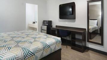 Een hotelkamer met een bed, een bureau, een stoel, een televisie en een grote spiegel.