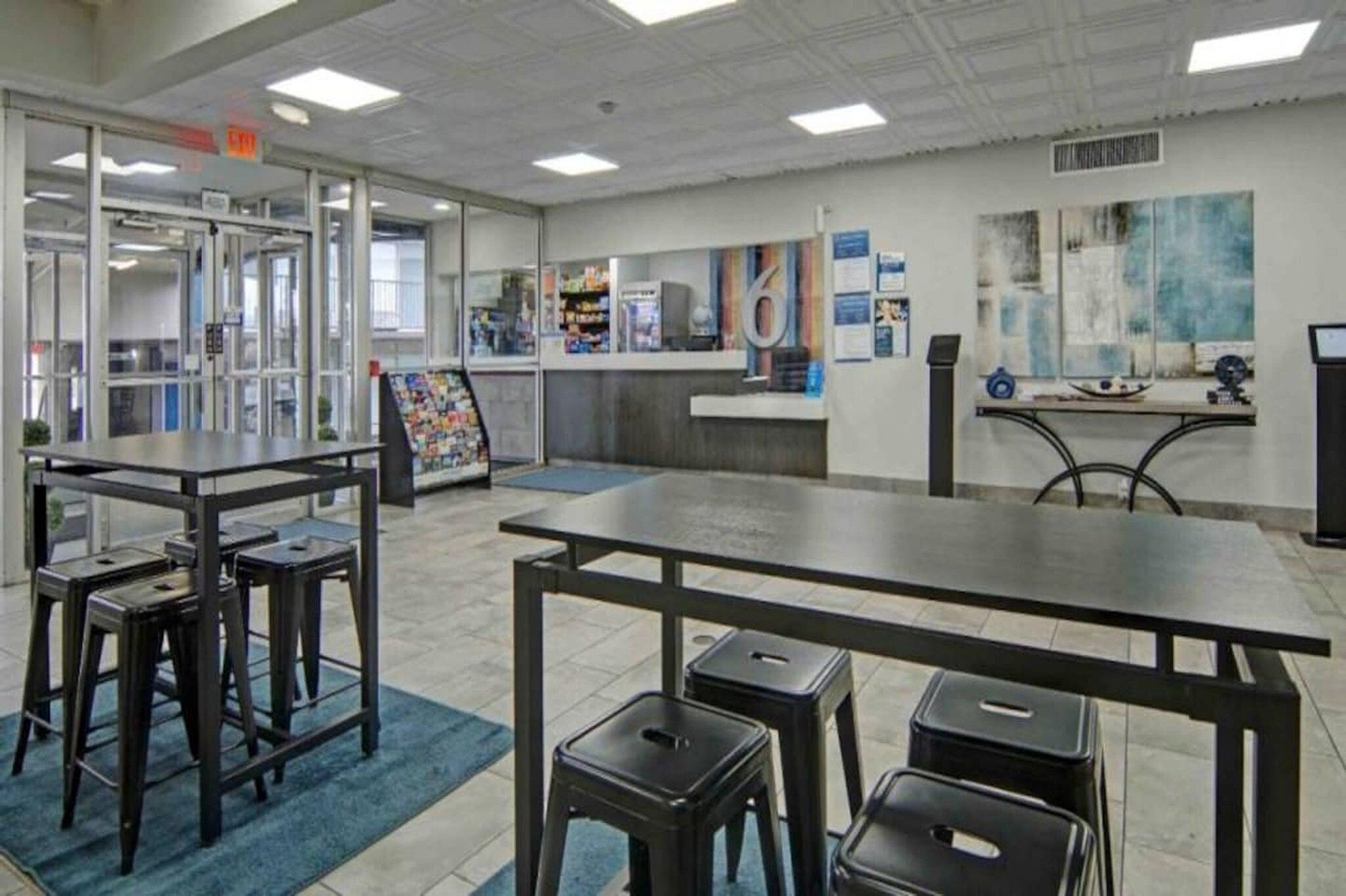 A modern interior with tables and stools, a bulletin board, and a counter.