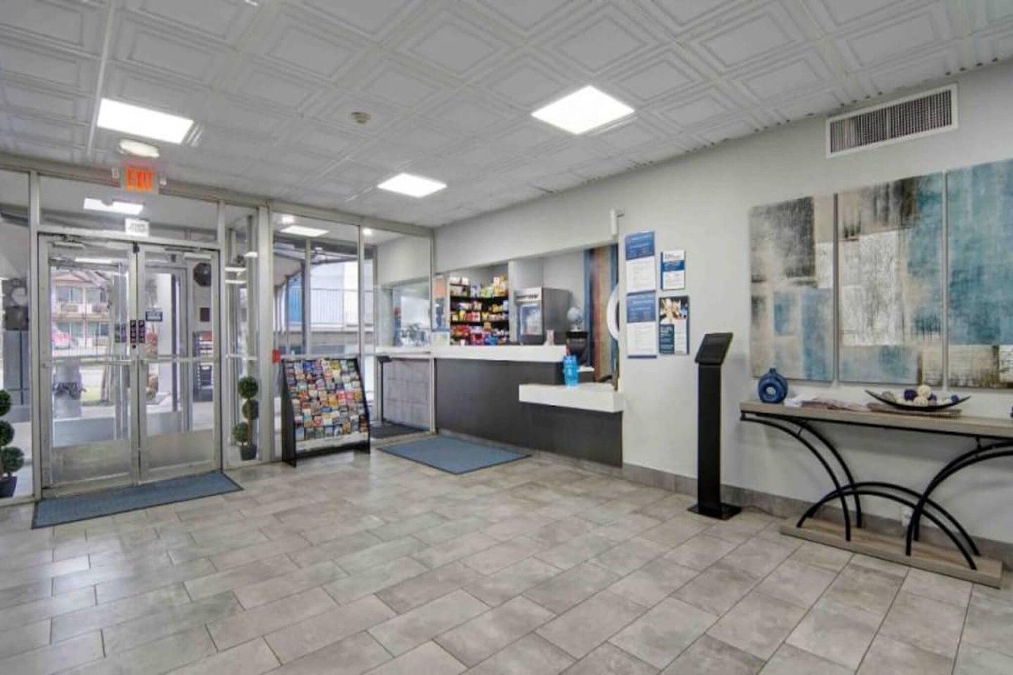A reception area with a glass door entrance, a counter with informational posters, and a tiled floor.
