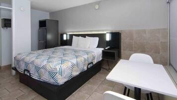 A hotel room with a bed, bedside table, nightstand, and a small table with chairs.