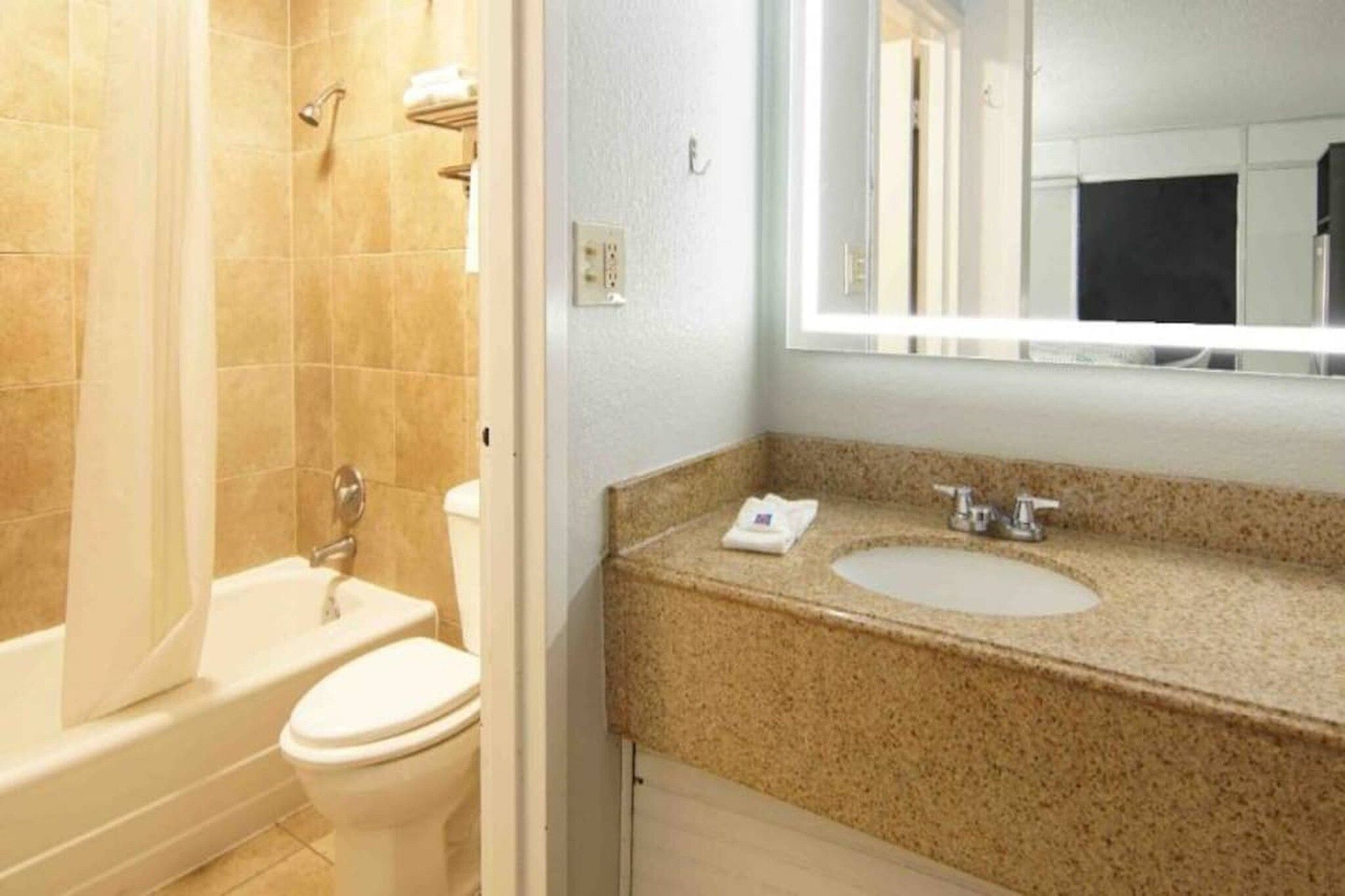 Et badeværelse med badekar, toilet, vask og spejl.
