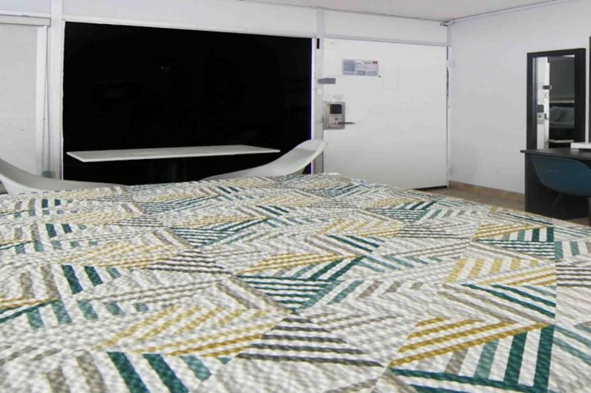 A hotel room with a bed, a desk, and a chair.