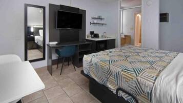 Een hotelkamer met een bed, een bureau, een stoel, een televisie en een spiegel.
