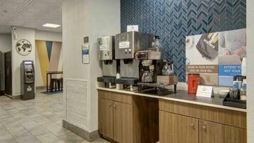 A coffee station with espresso machines, a coffee maker, and a sign promoting extended room service.