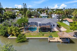 Ein Haus mit Schwimmbecken, umgeben von üppiger Vegetation und einem Wasserlauf.