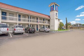 A motel with a parking lot, a two-story building, and a tower with the number 66. - 1 King Bed | Non-Smoking (Dallas)