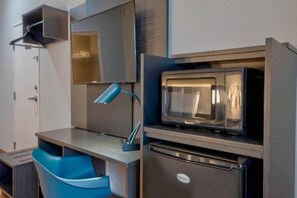 Eine kleine Küchenzeile mit Mikrowelle, Kühlschrank und Spüle.